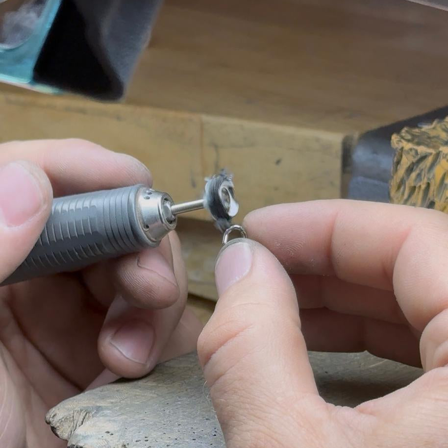 Photo d'une main tenant une boucle d'oreille sans fermoir Sédonia avec une polisseuse dans l'autre